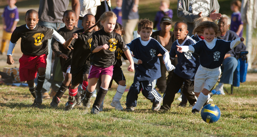 A group of young children chase a football